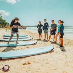 Group and instructor on beach with surfboards