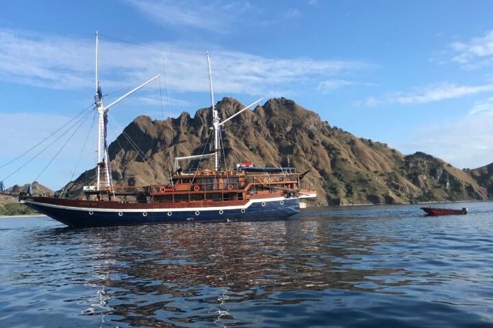 Sailing boat passing volcanic island
